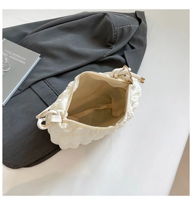 Detail view of white ruched handbag interior with bubble texture and gold hardware