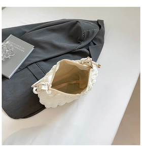 Close-up of white bubble quilted bag interior with top zipper and knotted handle detail