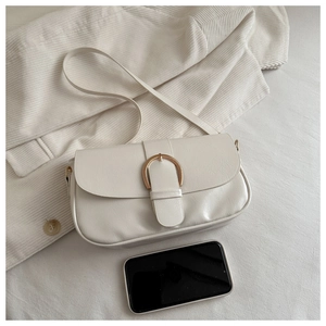 Gros plan d'un sac à bandoulière en similicuir blanc avec boucle dorée sur tissu