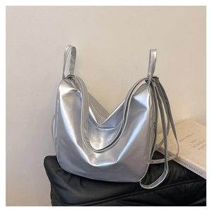Detail of silver metallic tote bag with reflective synthetic leather on a black leather bench