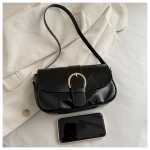 Sac à bandoulière noir brillant avec boucle dorée et smartphone pour comparer la taille