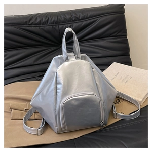 Detail of silver geometric backpack with triangular texture on a leather sofa