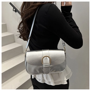 Détail du sac bandoulière argenté brillant avec boucle en métal vintage en forme de fer à cheval