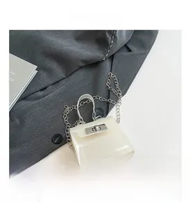 Primer plano del mini bolso blanco traslúcido con cierre giratorio plateado y cadena