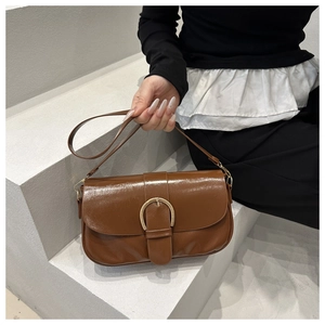 Détail du sac à main en cuir marron foncé avec une grande boucle fer à cheval dorée