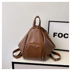 Detail view of brown leather triangular backpack featuring silver hardware and a front pocket