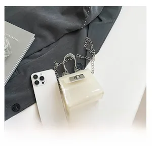 Mini bolso de gelatina en PVC blanco junto a un smartphone para comparar el tamaño