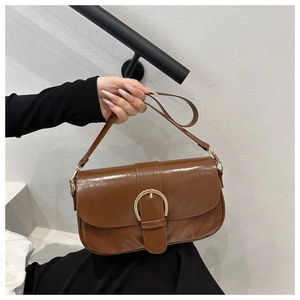 Gros plan d'un sac en cuir marron brillant doté d'une boucle en métal doré