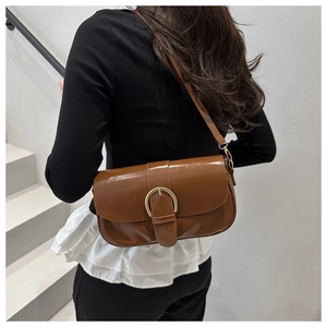 Gros plan d'un sac bandoulière en cuir marron avec une boucle en métal sur un mannequin
