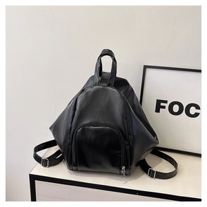 Detail of minimalist black PU leather backpack with geometric design and front zipper pocket