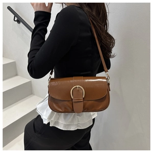Détail du sac besace vintage en cuir ciré marron avec boucle dorée sur le mannequin