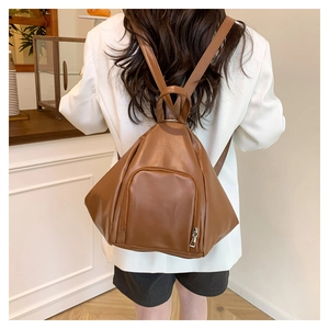 Rear view of a camel PU leather backpack on a model in a cozy indoor setting