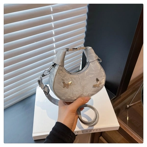 Détail du sac croissant argenté avec breloques papillons Y2K et texture plissée élégante