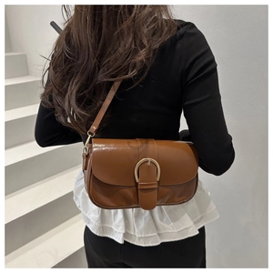 Sac bandoulière en cuir marron avec boucle fer à cheval dorée porté par mannequin