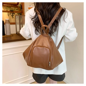 Caramel leather triangle backpack with front zipper pocket on white suit model