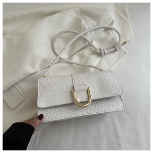 Detail of white woven texture bag with golden horseshoe clasp on corduroy background