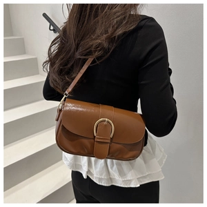 Détail d'un sac besace marron vintage en cuir huilé avec boucle en métal doré cavalier