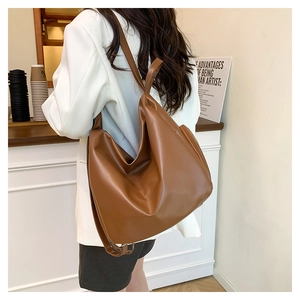 Lifestyle view of brown soft leather tote bag worn with a chic casual outfit