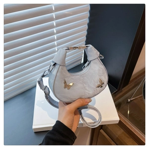 Détail du sac croissant bleu clair avec cuir plissé et breloques papillon en argent