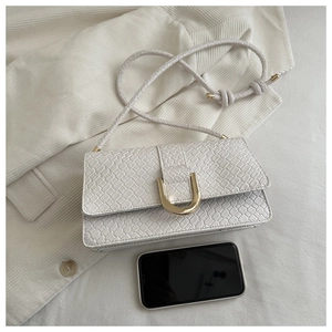 Close-up of white embossed leather handbag featuring a signature golden U-shaped buckle