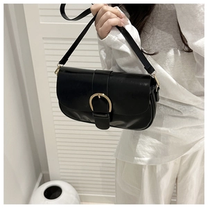Gros plan d'un sac bandoulière en cuir noir brillant avec boucle en métal dorée