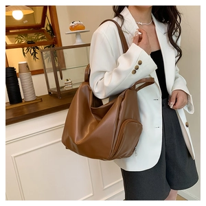Brown soft leather tote bag with a side zipper pocket in a cozy cafe setting