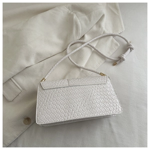 Detail of white textured shoulder bag with knotted strap and gold metal hardware