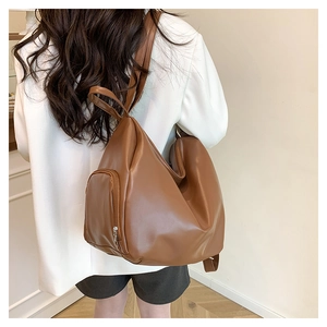 Detail of a brown faux leather backpack with side metal zipper shown on a model