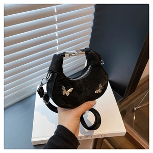 Détail du sac demi-lune noir avec papillons argentés et fermeture à boucle métallique