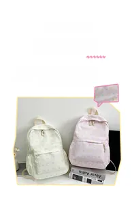 Detail of cute cat printed backpacks in cream and pink colors with front pockets