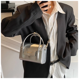 Detail of a silver mini square handbag with metal finish and golden brand logo on flap
