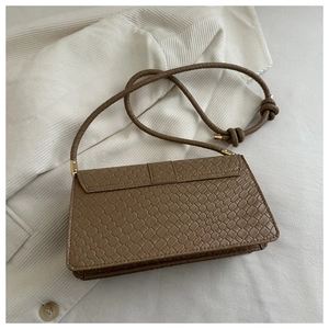 Detail of light brown crocodile pattern leather baguette bag with knotted shoulder strap