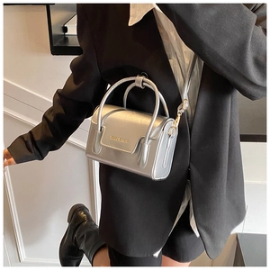 Close-up of metallic silver mini square bag with gold logo and mirror-like finish