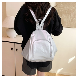 Rear view of silver metallic PU leather backpack shown in a minimalist home setting