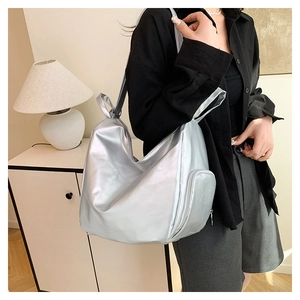 Silver metallic PU tote bag showing side zipper pocket detail on model in home setting