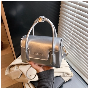 Detail of silver metallic handbag with gold logo lettering and smooth leather texture