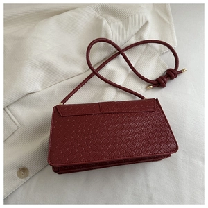 Detail of burgundy woven texture leather bag with elegant golden knot strap ends