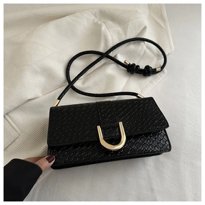 Close-up of black embossed woven texture handbag with golden U-shaped metal buckle