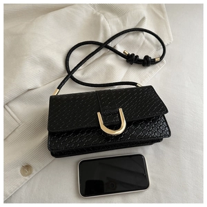 Close-up of black woven texture and gold U-shaped buckle on a stylish shoulder bag