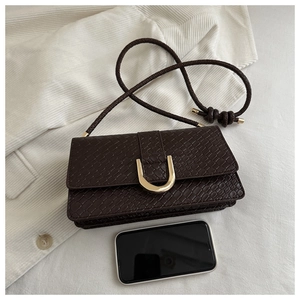 Close-up of brown crocodile pattern handbag with golden U-buckle and woven strap