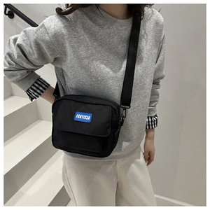 Lifestyle shot of black nylon crossbody bag with adjustable strap and front pocket