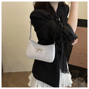 Detail of woven texture and golden bow on a white chic crescent underarm bag