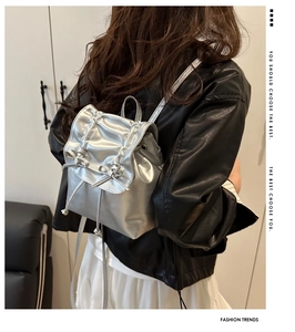 Details des silbernen Metallic-Rucksacks mit Schleife und glatter Metallstruktur