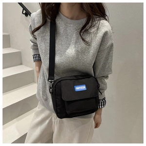 Close-up of the black nylon crossbody bag with a blue FANYISSA brand label and strap detail