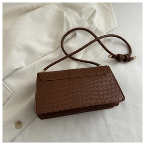 Detailed view of dark brown woven texture shoulder bag with knotted strap and gold hardware