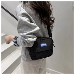 Detail view of the black crossbody bag with adjustable strap and blue FANYISSA logo label