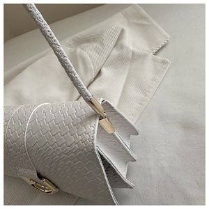 Close-up of white woven texture shoulder bag featuring gold hardware and pleated side detail