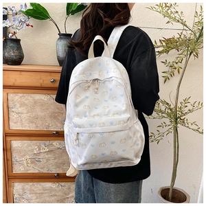 Lifestyle shot of white canvas backpack with cute cat patterns and blue bow details