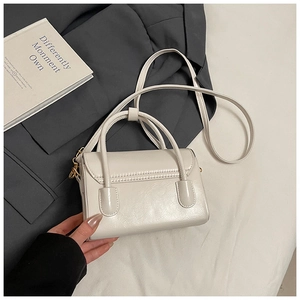 Detail of white mini leather handbag with gold hardware and adjustable strap on a suit