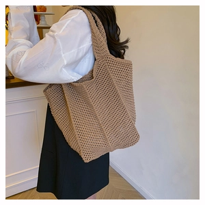 Close-up of a khaki woven straw tote bag featuring intricate crochet texture and wide strap